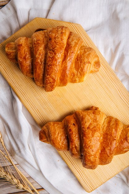 Dos croissants franceses en la tabla de cortar de madera