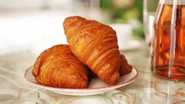 Dos croissants recién hechos en un plato sobre una mesa de cristal. Concepto de desayuno y productos recién horneados.