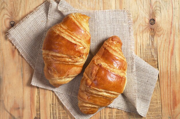 Dos croissants recién hechos en la vista superior de fondo de madera vieja