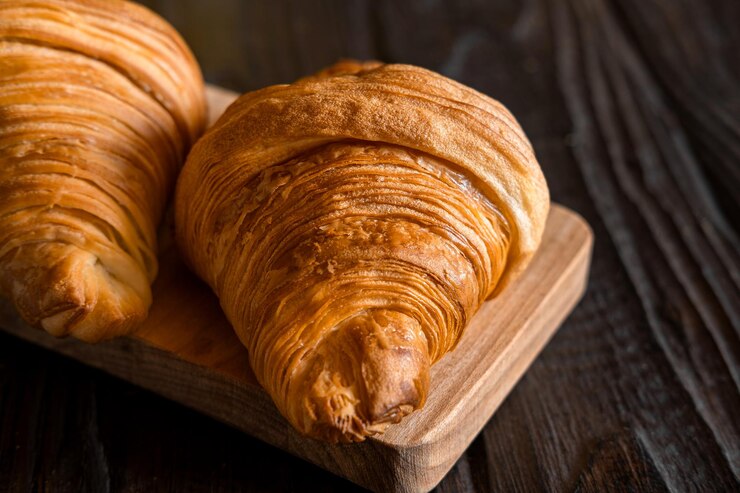 Dos croissants en una tabla de corte de madera rústica mesa oscura comida pancarta deliciosa mermelada de croissants frescos