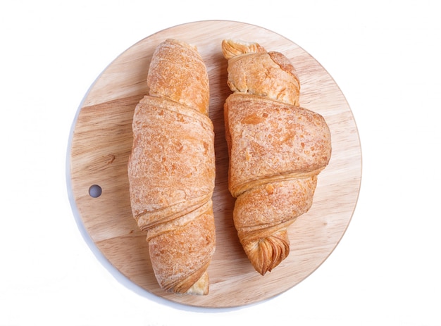 Dos croissants en el tablero de madera de la cocina aislado en el fondo blanco