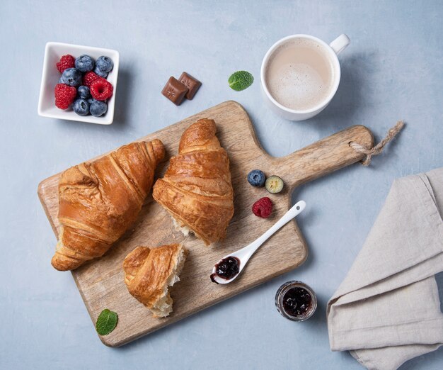 Dos croissants con una taza de café y bayas.