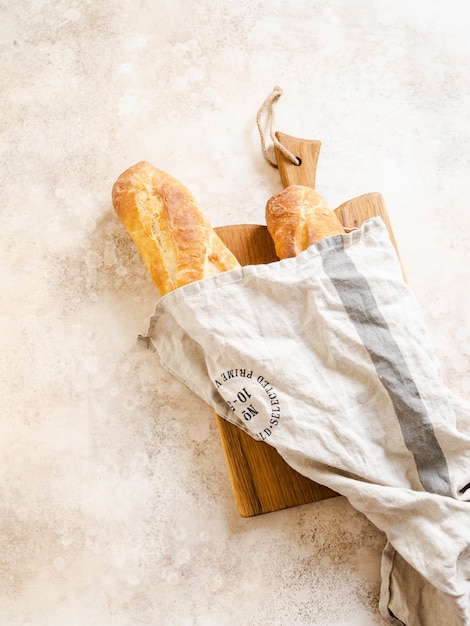 Foto dos crujientes baguettes francesas caseras frescas sobre tabla para cortar madera en el sol sobre la mesa