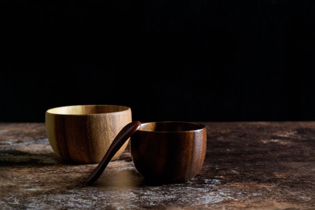 Foto dos cuencos de madera de estilo japonés con cuchara de madera sobre fondo marrón grunge oscuro con espacio para copiar