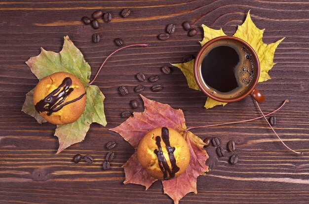 Dos cupcakes con chocolate y taza de café en madera, vista superior