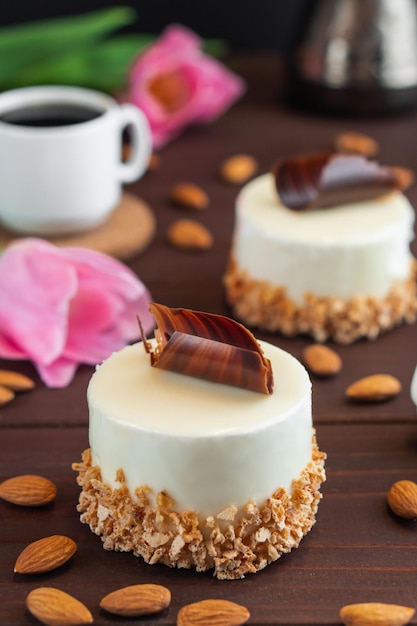 Dos cupcakes con taza de café con leche de chocolate, almendras y tulipanes en la mesa de madera Enfoque selectivo