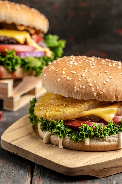 Dos deliciosas hamburguesas caseras de ternera, queso y verduras. Alimentos grasos no saludables. imagen vertical. lugar para el texto.