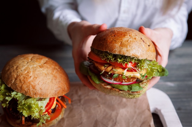 Dos deliciosas hamburguesas vegetarianas deliciosas sobre una superficie de madera negra.