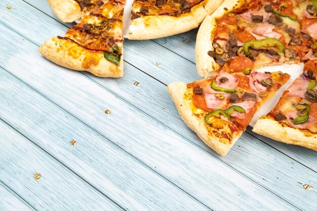 Dos deliciosas pizzas grandes diferentes sobre un fondo de madera azul.