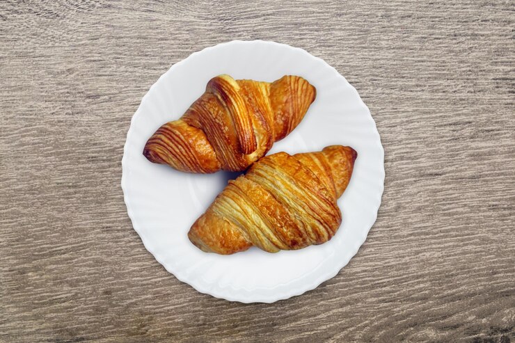Dos deliciosos croissants en un plato blanco Desayuno francés de mañana con pasteles frescos