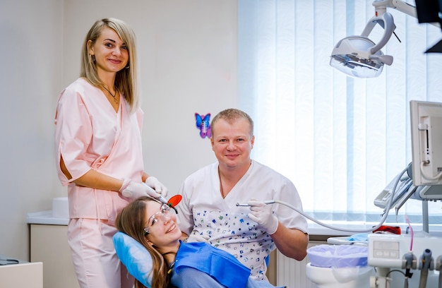 Dos dentistas examinan los dientes del paciente para el tratamiento posterior Gabinete de estomatología moderno