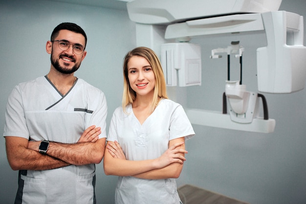 Dos dentistas de pie en la sala de rayos xy posando