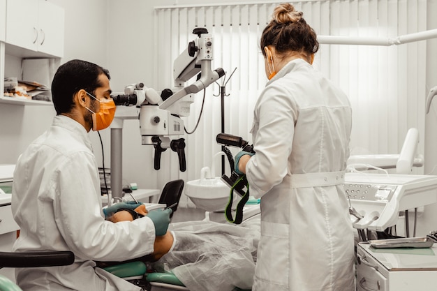 Dos dentistas tratan a un paciente. Uniforme profesional y equipamiento de un dentista. Asistencia sanitaria Equipar un lugar de trabajo de médicos. Odontología