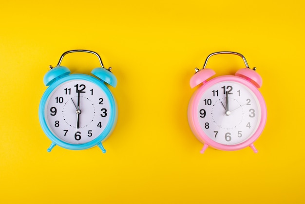 Foto dos despertadores en amarillo que muestran una hora diferente como el concepto de una persona de la mañana