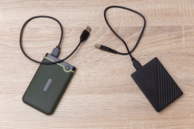 Dos discos duros externos con cable en una mesa de madera