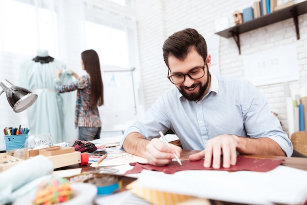 Dos diseñadores de moda haciendo recortes en cuero.