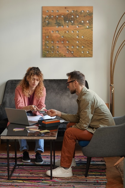 Dos diseñadores sentados en el sofá y trabajando en un nuevo proyecto que examinan los patrones juntos en la oficina