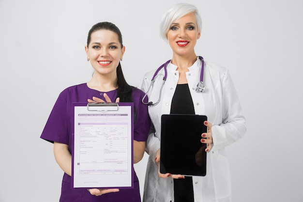 Dos doctoras con tableta y hoja con análisis en manos aisladas