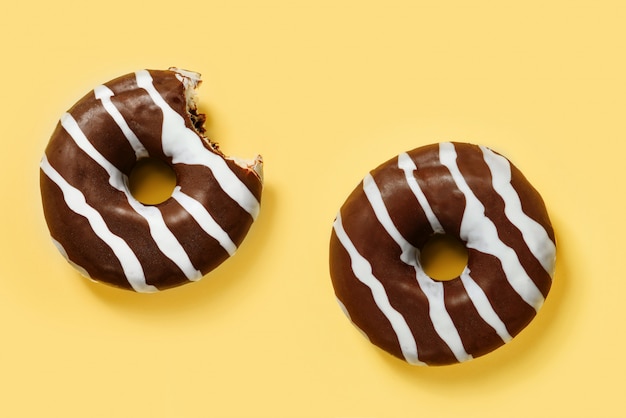 Dos donas de chocolate sobre un fondo amarillo