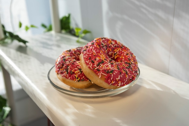 Dos donas frescas en un plato sobre un estante blanco al sol.