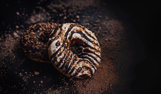 Dos donuts con glaseado blanco y glaseado de chocolate se encuentran sobre un fondo negro