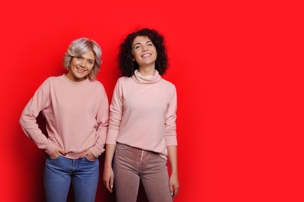 Dos dulces mujeres posando en un rojo en los mismos suéteres