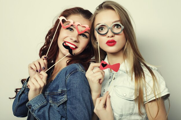 Dos elegantes chicas sexy hipster mejores amigos listos para la fiesta, sobre superficie gris