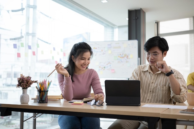 Dos empleados de inicio que consultan con una tableta digital en una oficina moderna