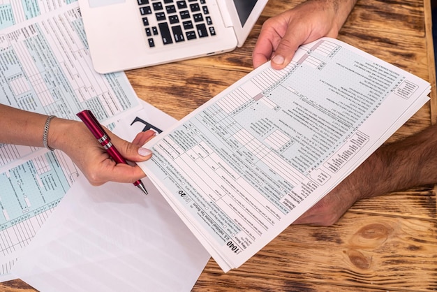 Foto dos empleados en el trabajo llenan los formularios de impuestos 1040 en el escritorio de la oficina