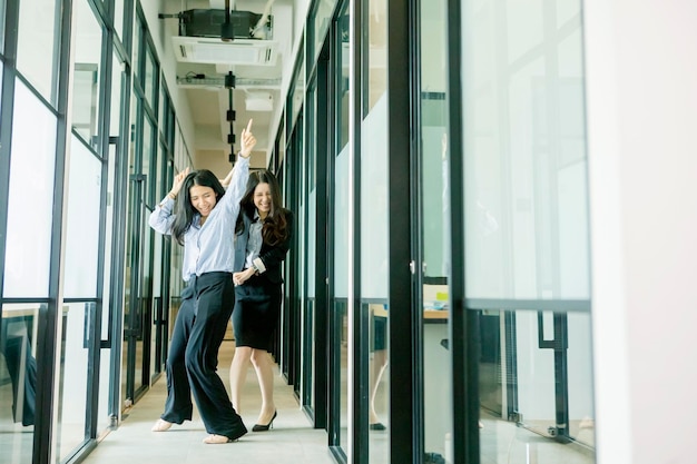 Dos empresaria feliz bailando en el pasillo de la oficina