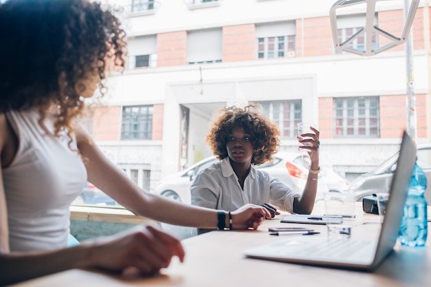 Dos empresarias jóvenes que hablan en la oficina moderna