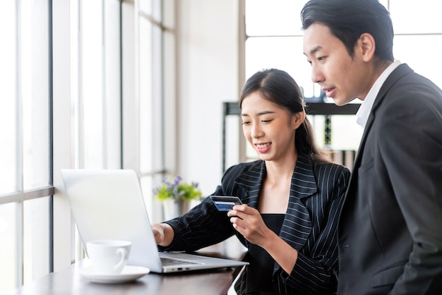 Dos empresarios asiáticos usan una tarjeta de crédito para pagos en línea Empresarios compran en línea