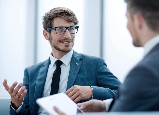 Dos empresarios confiados que usan una tableta digital juntos mientras trabajan en una mesa en la oficina