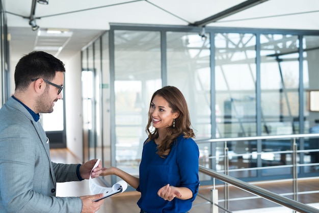 Dos empresarios conversando en el pasillo de la empresa.