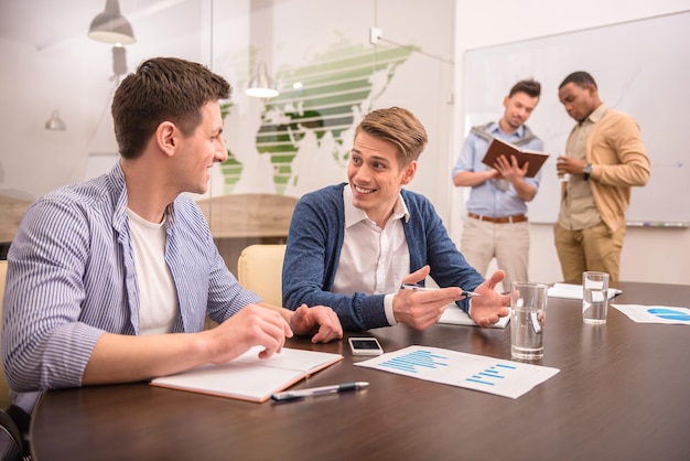 Dos empresarios están hablando sentados en la mesa en el fondo de colegas