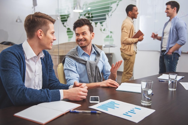 Dos empresarios están hablando sentados en la mesa en el fondo de colegas