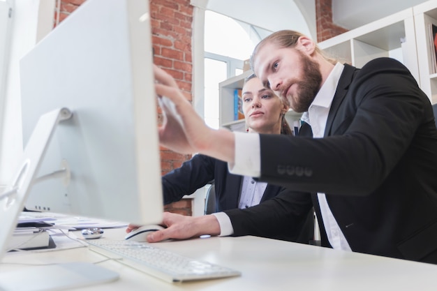 Dos empresarios mirando el monitor sentado en la oficina