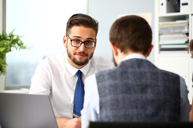 Dos empresarios oficinistas sonrientes deliberan sobre el problema