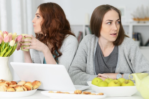 dos, enojado, mujeres jóvenes, sentado, en la mesa