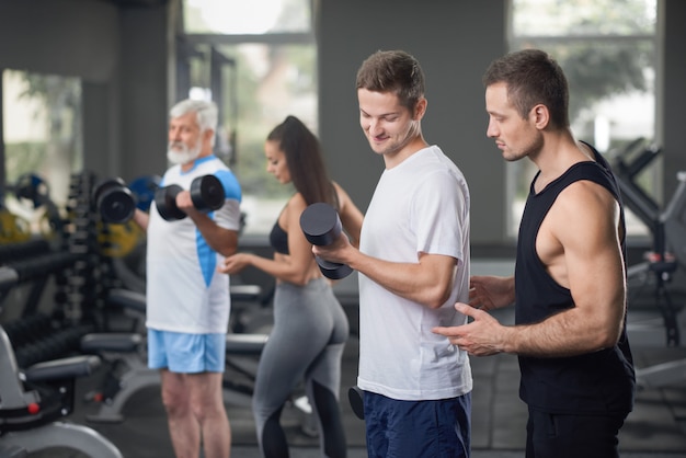 Dos entrenadores que trabajan con clientes en el gimnasio.