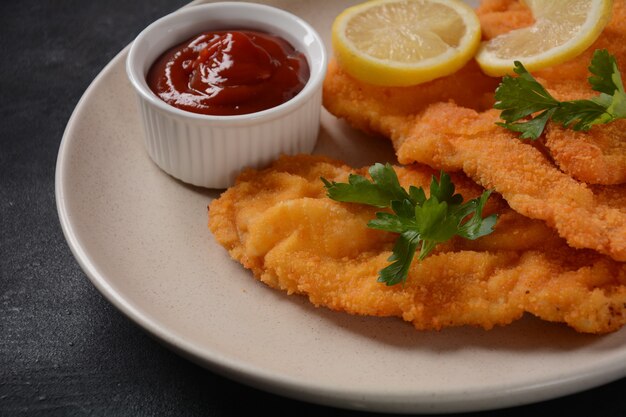 Dos escalopes de pollo empanizado con limón en la placa