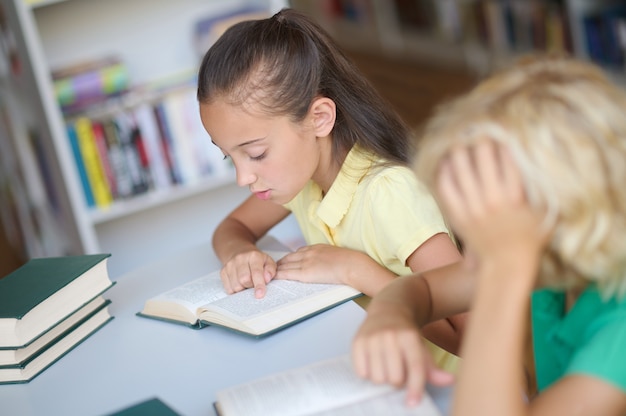 Dos escolares enfocados que estudian juntos en la biblioteca.