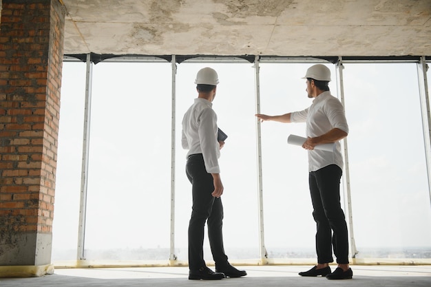 Dos especialistas inspeccionan el proyecto inmobiliario del sitio de construcción de edificios industriales comerciales con el ingeniero civil