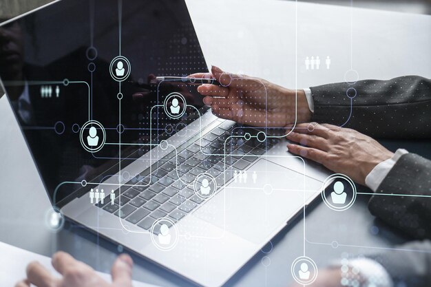 Dos especialistas en recursos humanos que analizan el mercado de contratación utilizando una computadora portátil para impulsar el programa de pasantías en una empresa de consultoría internacional Iconos de hologramas de redes sociales