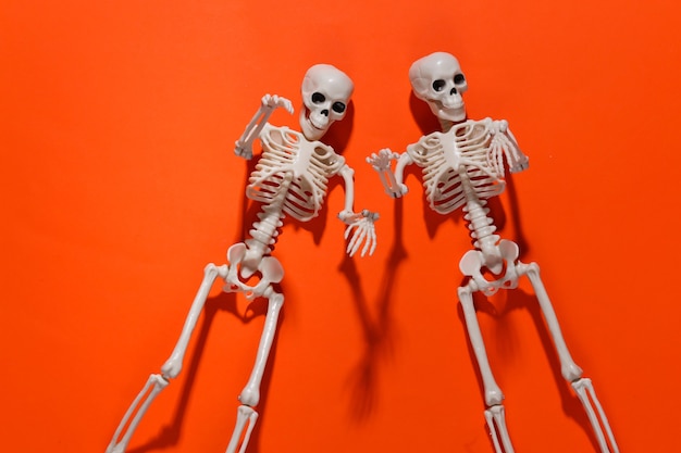 Dos esqueletos falsos en naranja brillante. Decoración de Halloween, tema de miedo