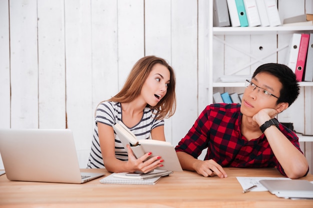 Dos estudiantes aprendiendo con laptop y libros.