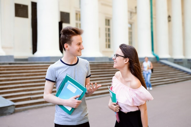 Dos estudiantes felices caminando y hablando cerca del antiguo campus después de clases