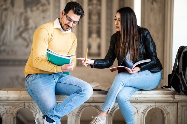 Dos estudiantes que estudian en interiores en un espacio abierto universitario