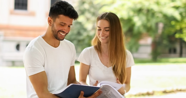 Dos estudiantes que estudian juntos sentados en un banco al aire libre