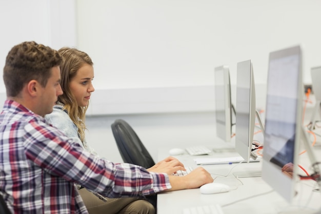 Dos estudiantes serios que trabajan en la computadora